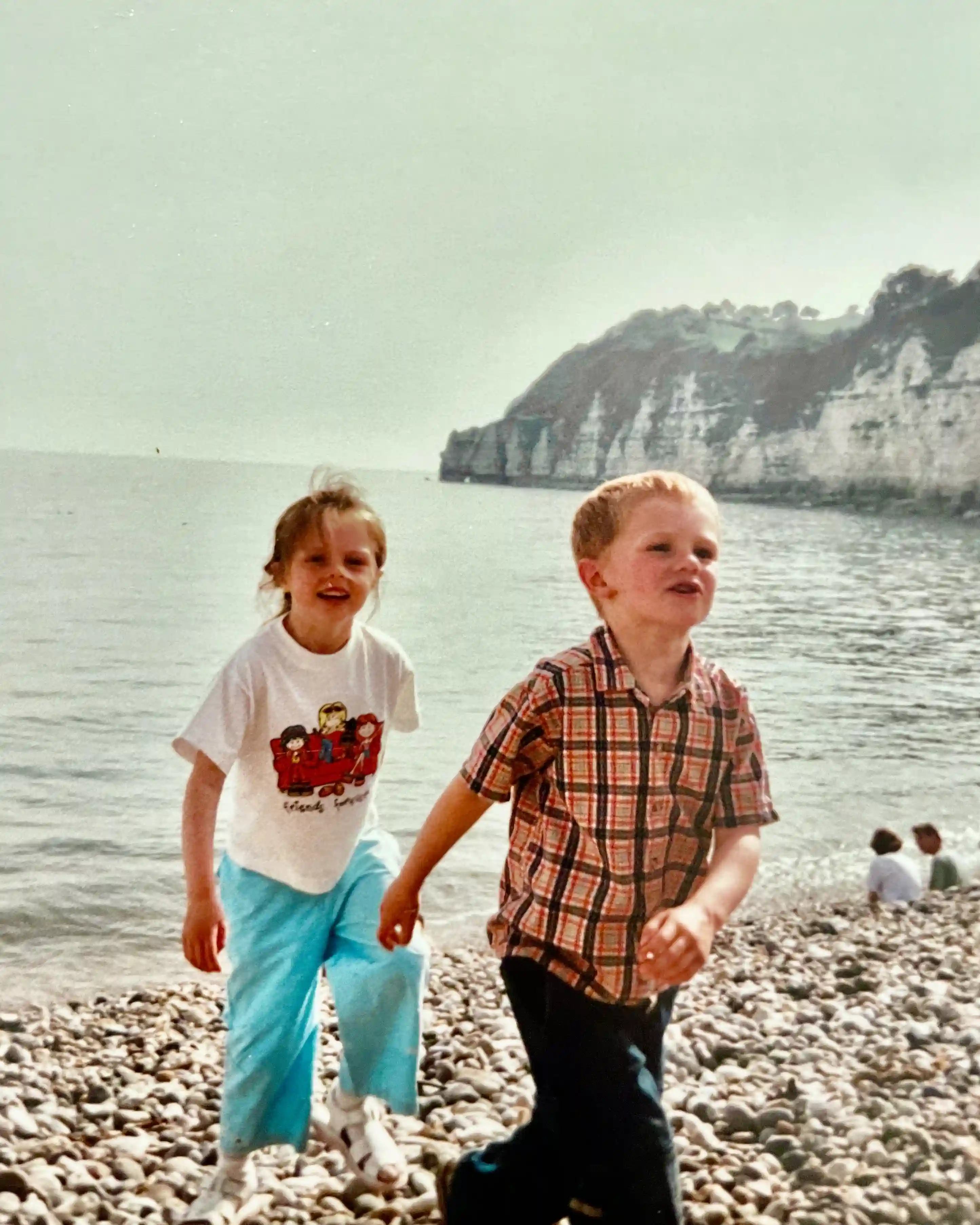 Noah and his sister Molly as children walking up the beach towards the camera